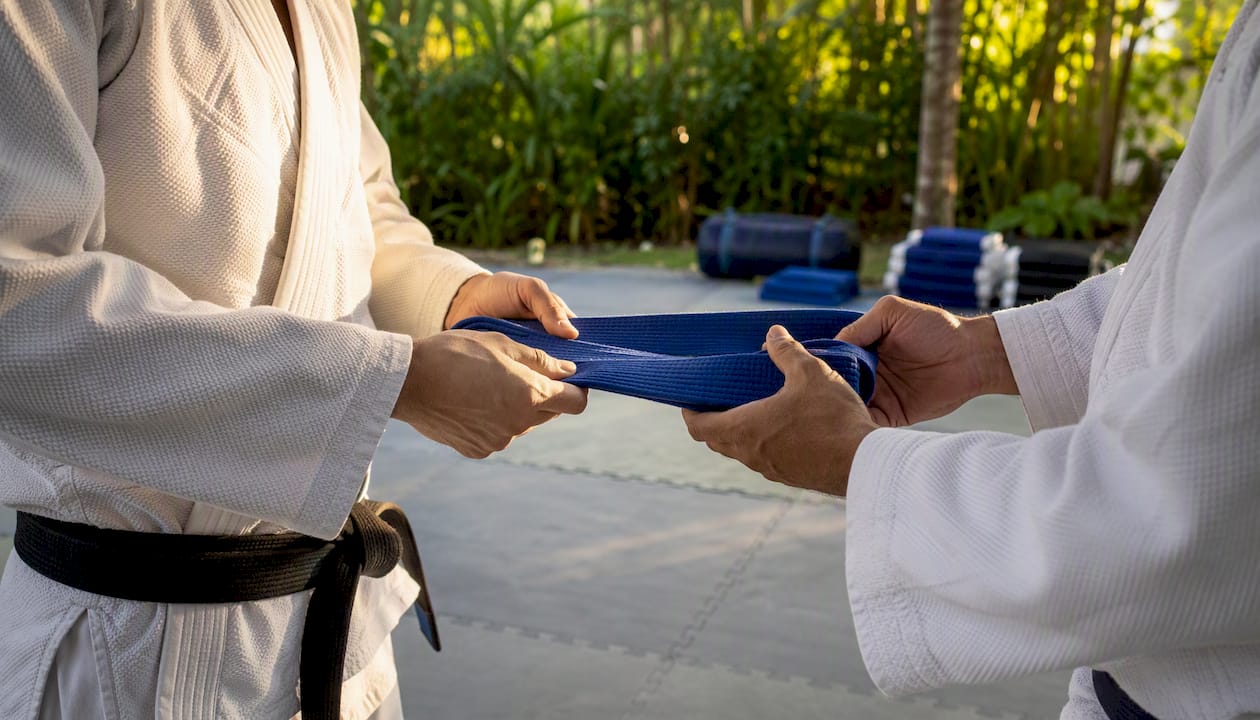 Hands exchanging martial arts belt at ceremony