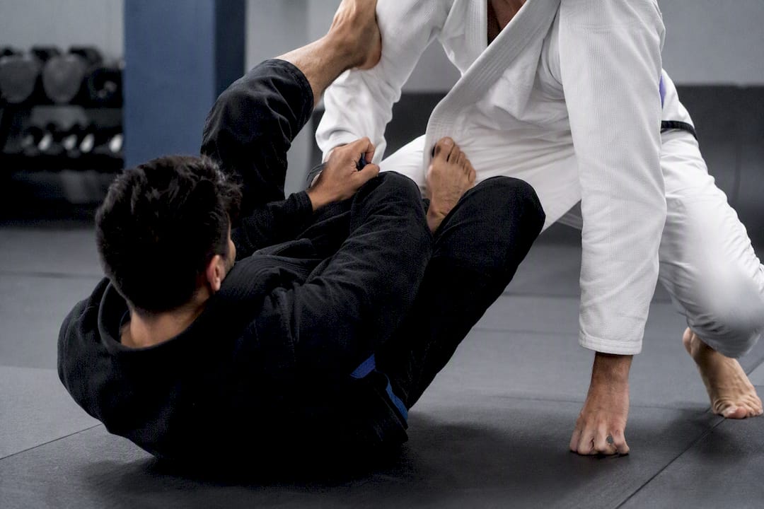 Two martial artists grappling in BJJ class