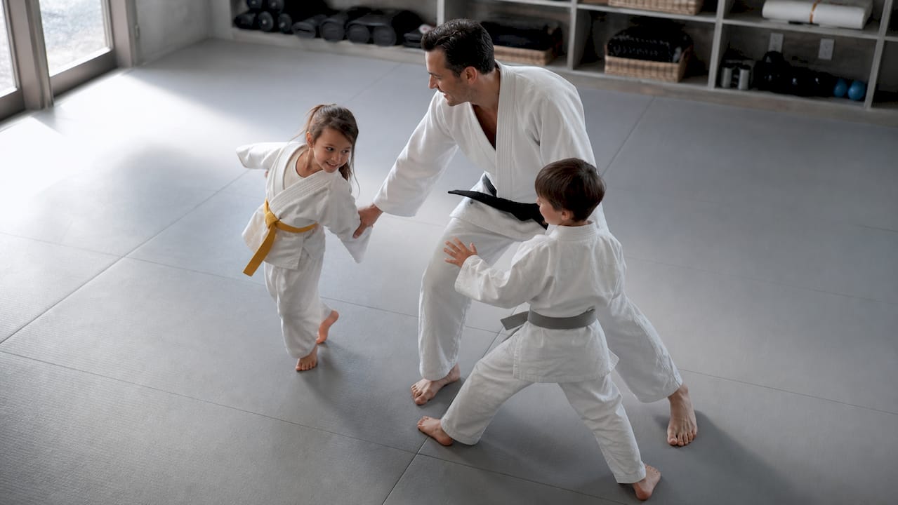 Family training on dojo mats with varied belt colors