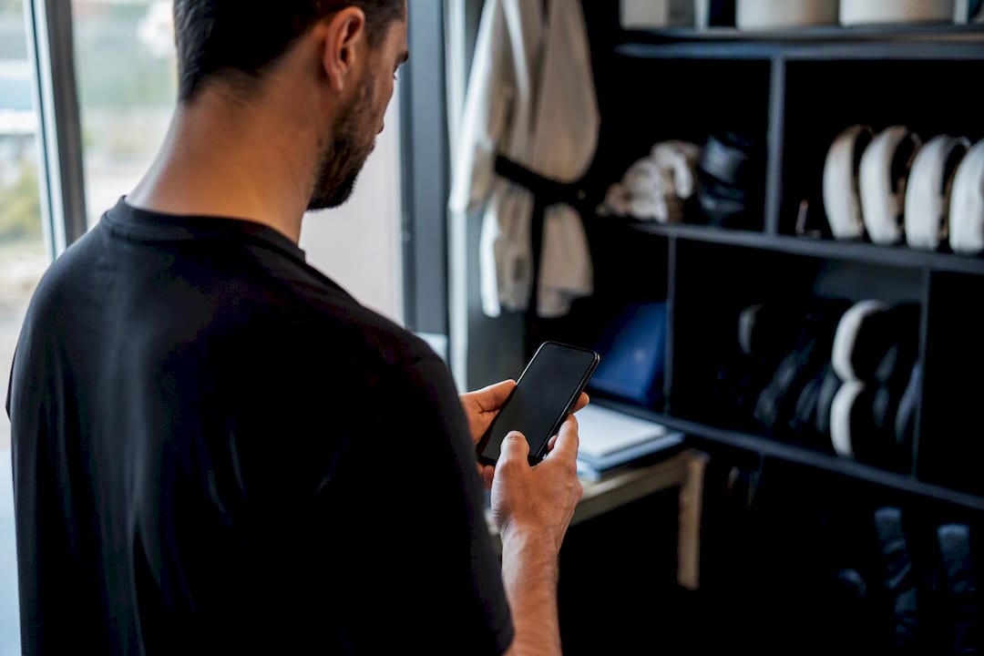 Hands operating phone in martial arts studio corner