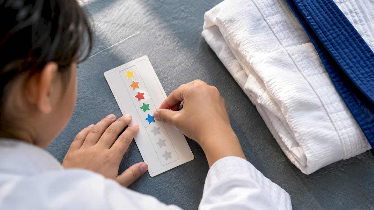 Child adding sticker to attendance reward card